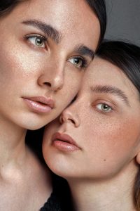 Two women with minimal make up cheek to cheek