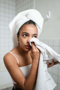 woman in a bathroom drying her face with a towel