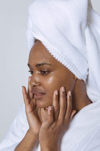 woman with plump moisturised skin decoratively touching her face